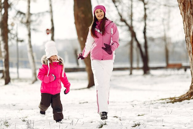 Famille en chapeaux d'hiver tricotés en vacances de Noël en famille. Femme et petite fille dans un parc. Les gens jouent.