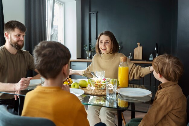 Famille chrétienne souriante mangeant ensemble coup moyen