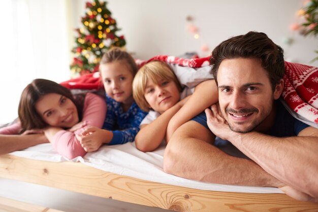 Famille couchée dans son lit au moment de Noël