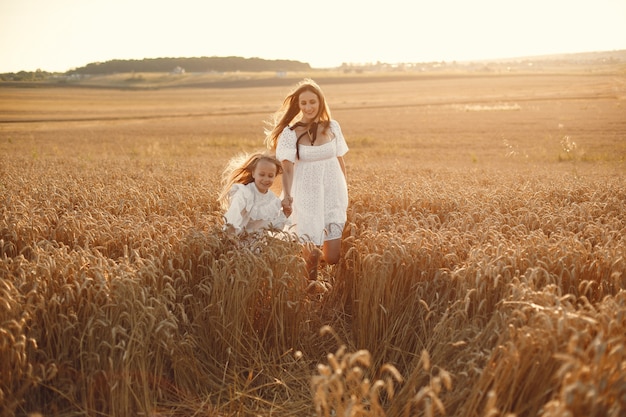 Famille dans un champ de blé. Femme en robe blanche. Fille au chapeau de paille.