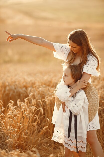 Famille dans un champ de blé. Femme en robe blanche. Fille au chapeau de paille.