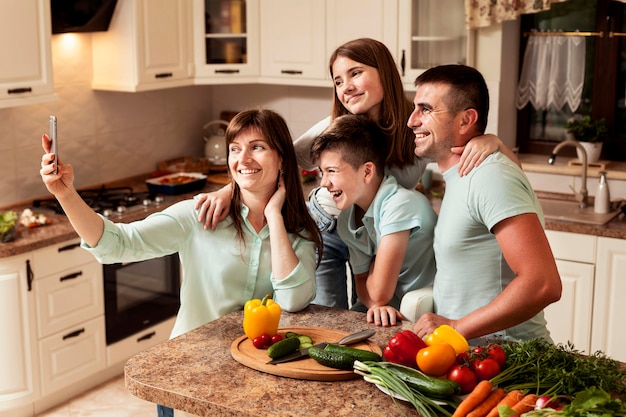 Famille dans la cuisine prenant un selfie tout en préparant la nourriture