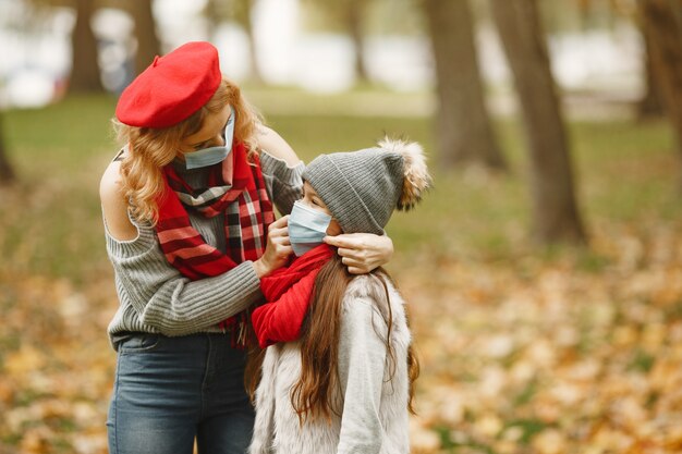 Famille dans un parc d'automne. Thème du coronavirus. Mère avec fille.