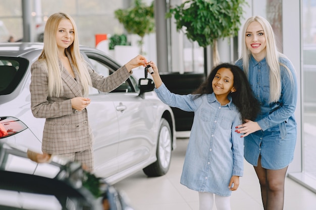 Photo gratuite famille dans un salon de voiture. femme achetant la voiture. petite fille africaine avec mther. manager avec les clients.