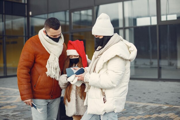 Famille debout à l'extérieur portant un masque facial et vérifiant les passeports