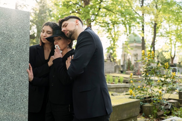 Famille en deuil vêtue de noir pleurant sur une tombe du cimetière