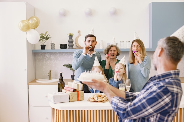 Photo gratuite la famille et deux de leurs filles fêtent l'anniversaire des grands-mères. le fils adulte garde un gâteau avec des bougies