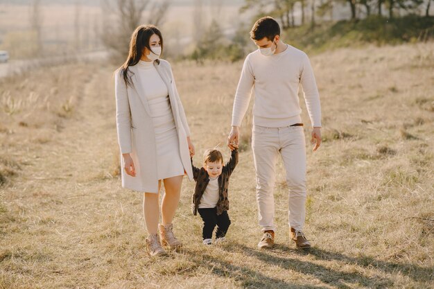 Famille élégante portant des masques marchant sur un champ de printemps