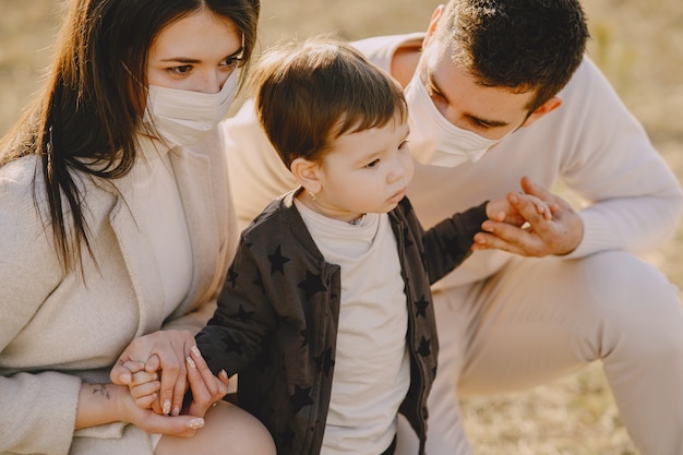 Famille élégante portant des masques marchant sur un champ de printemps