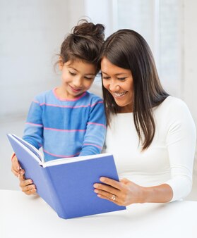 Famille, enfants, éducation, école et concept de personnes heureuses - mère et fille avec livre