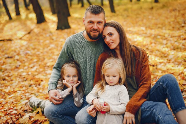 Famille avec enfants mignons dans un parc en automne