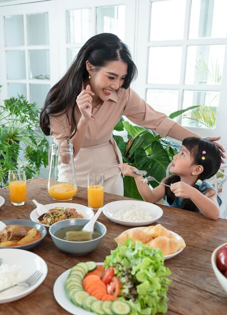 Une famille heureuse asiatique passe du temps à déjeuner sur la table ensemble relation et activité dans la maison