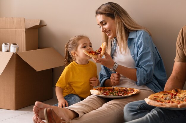 Famille heureuse ayant une pizza dans leur nouvelle maison