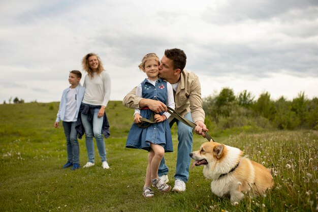 Famille heureuse avec chien à l'extérieur plein coup