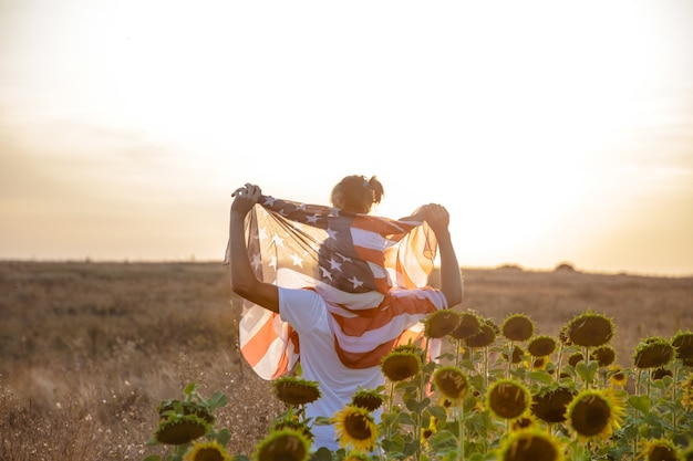 Une famille heureuse avec un drapeau américain au coucher du soleil.