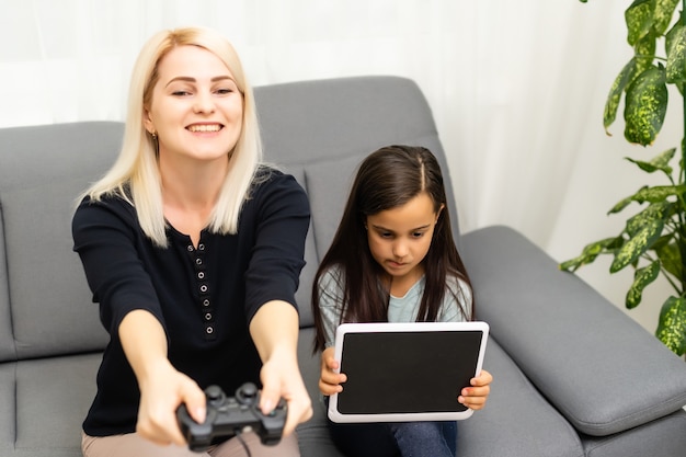 Famille heureuse ensemble. mère et sa petite fille jouant à des jeux vidéo. famille se détendre.