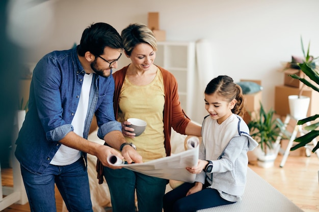 Famille heureuse passant par des plans de logement tout en emménageant dans une nouvelle maison