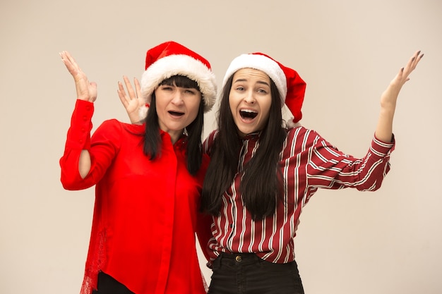 Famille heureuse en pull de Noël posant. Profiter des câlins d'amour, des gens de vacances. Maman et doughter sur fond gris dans le studio