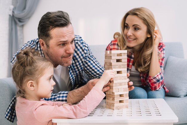 Famille jouant avec des blocs de bois sur la table dans le salon