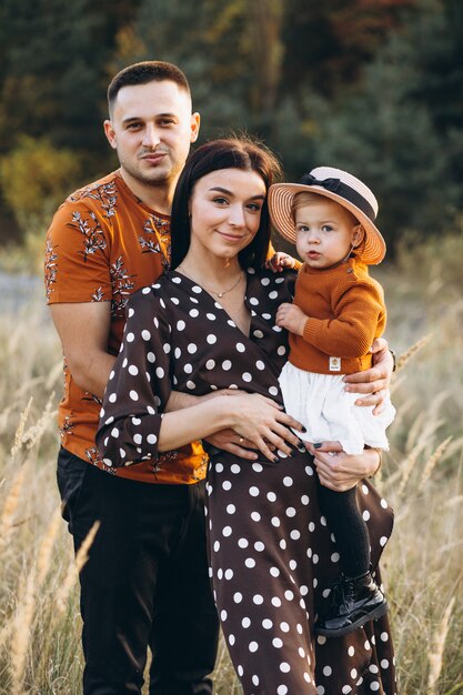 Famille avec leur petite fille dans un champ d'automne