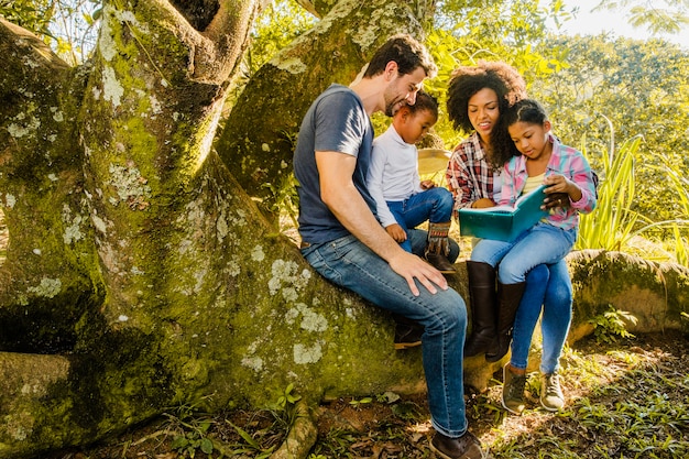 La famille lisant ensemble sur un tronc d&#39;arbre