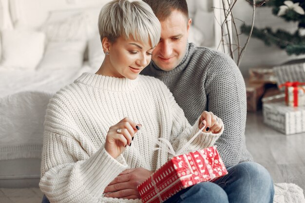 Famille à la maison. Couple près de décorations de Noël. Femme dans un pull gris.