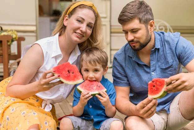 Famille mangeant ensemble de la pastèque à côté d'une caravane