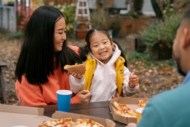 Famille mangeant de la pizza à l'extérieur vue latérale