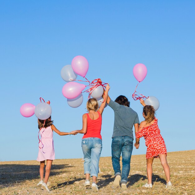 Famille marchant dans le champ avec des ballons