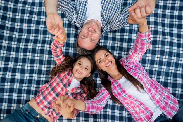 Famille, mensonge, sur, bleu, damier, couverture, tenant mains, dans, jardin