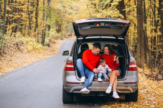 Famille avec un petit fils en automne parc assis dans la voiture