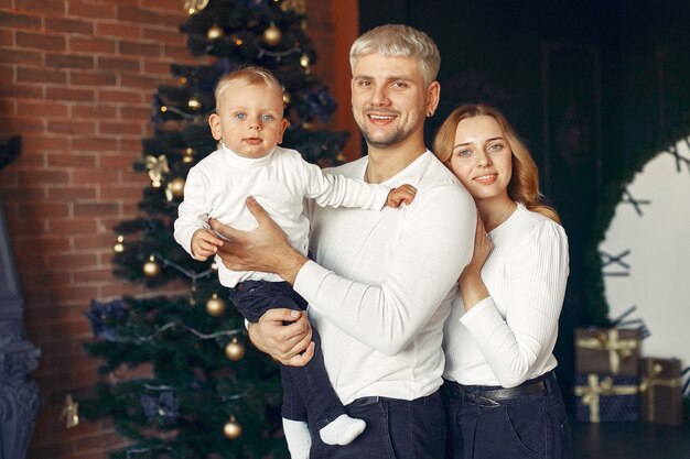 Famille avec petit fils à la maison près de l'arbre de Noël