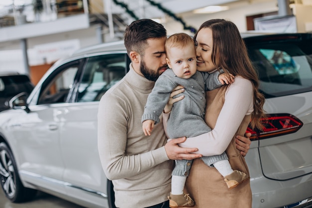 Famille avec petite fille choisissant une voiture dans un salon de l'automobile