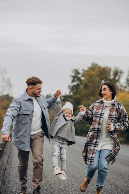 Famille avec petite fille ensemble par temps d'automne s'amusant