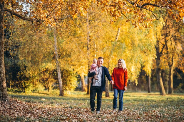 Famille avec petite fille marchant dans un parc en automne