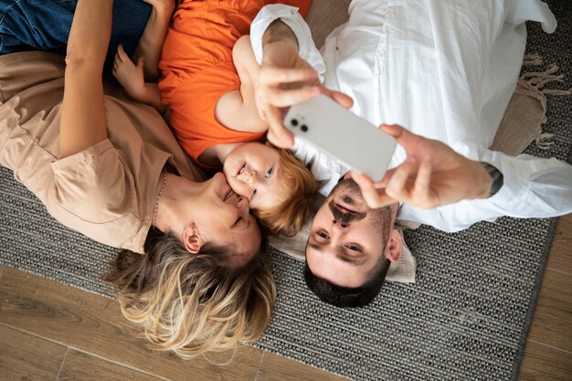 Famille de plan moyen prenant un selfie avec un smartphone