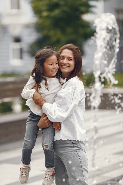 Famille près de la fontaine de la ville. Mère avec jauge jouant avec de l'eau.