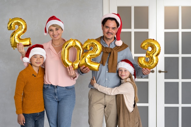 Famille de quatre personnes célébrant le nouvel an à la maison ensemble