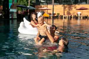 Photo gratuite famille de quatre personnes profitant d'une journée à la piscine ensemble