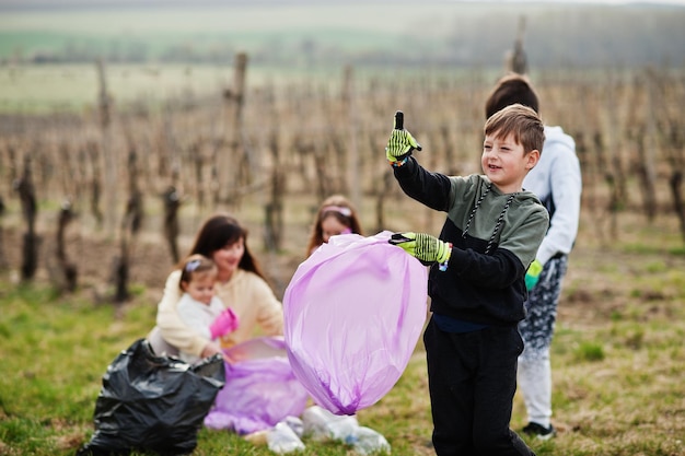 Photo gratuite famille avec sac poubelle ramassant les ordures pendant le nettoyage dans les vignes conservation de l'environnement et recyclage écologique