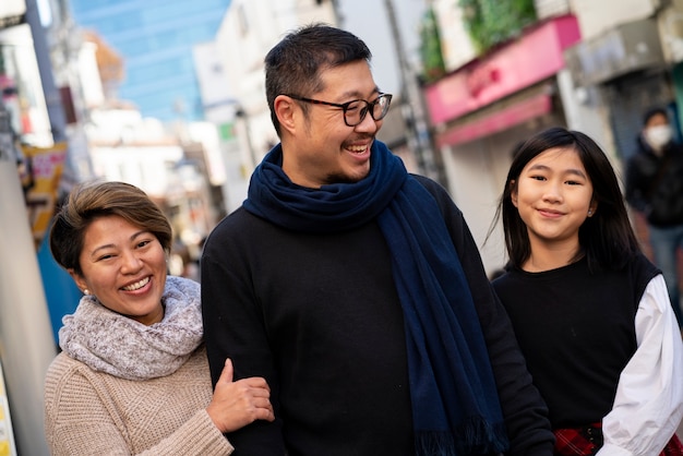 Famille souriante de plan moyen à l'extérieur