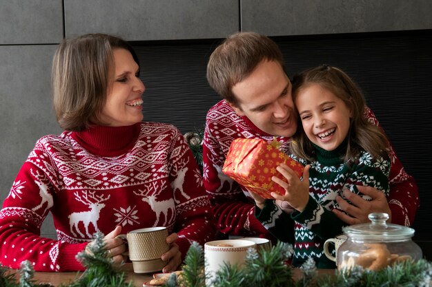 Famille souriante de plan moyen à la maison