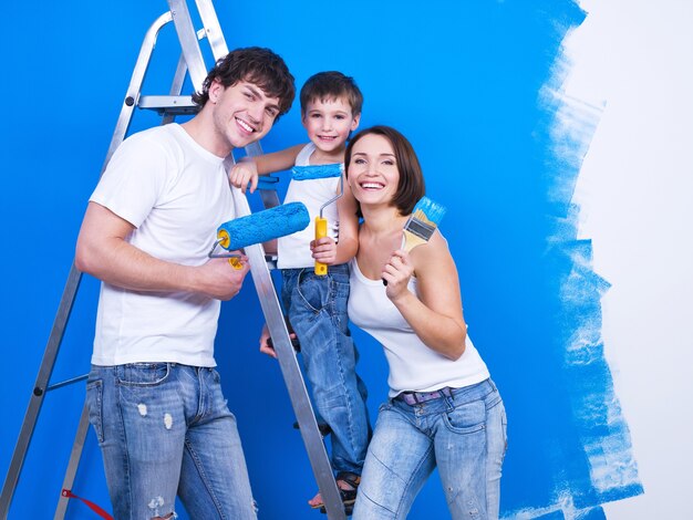 Famille souriante sympathique avec jeune fils peignant le mur