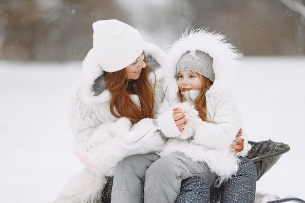 Famille En Vacances De Noël En Famille. Femme Et Petite Fille Dans Un Parc.  Les Gens Avec Un Traîneau.