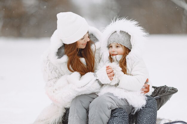 Famille en vacances de Noël en famille. Femme et petite fille dans un parc. Les gens avec un traîneau.