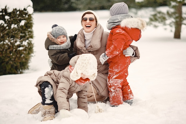 Famille en vêtements d'hiver en vacances dans la forêt enneigée