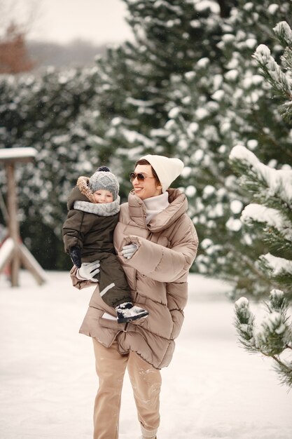 Famille en vêtements d'hiver en vacances dans la forêt enneigée