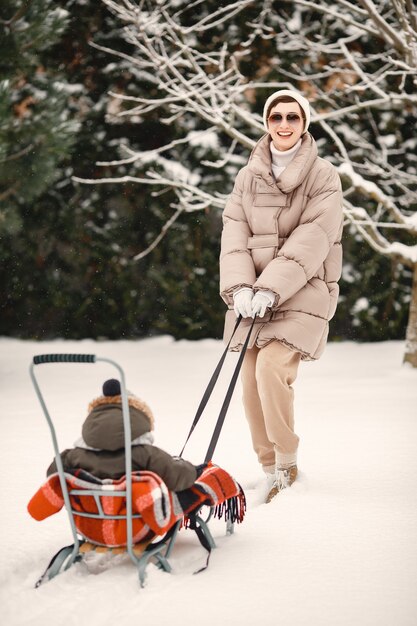 Famille en vêtements d'hiver en vacances dans la forêt enneigée