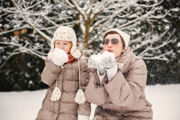 Famille en vêtements d'hiver en vacances dans la forêt enneigée