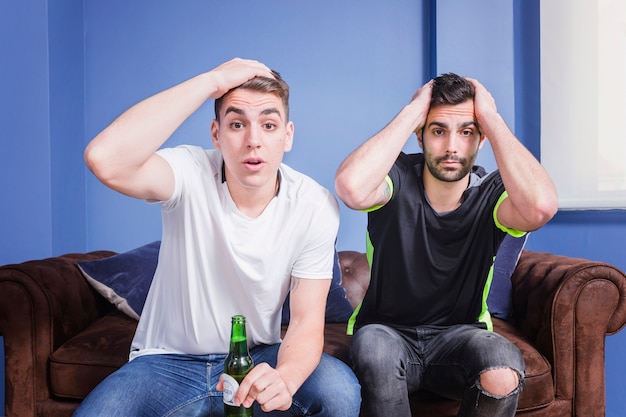 Photo gratuite les fans de football avec de la bière sur le canapé